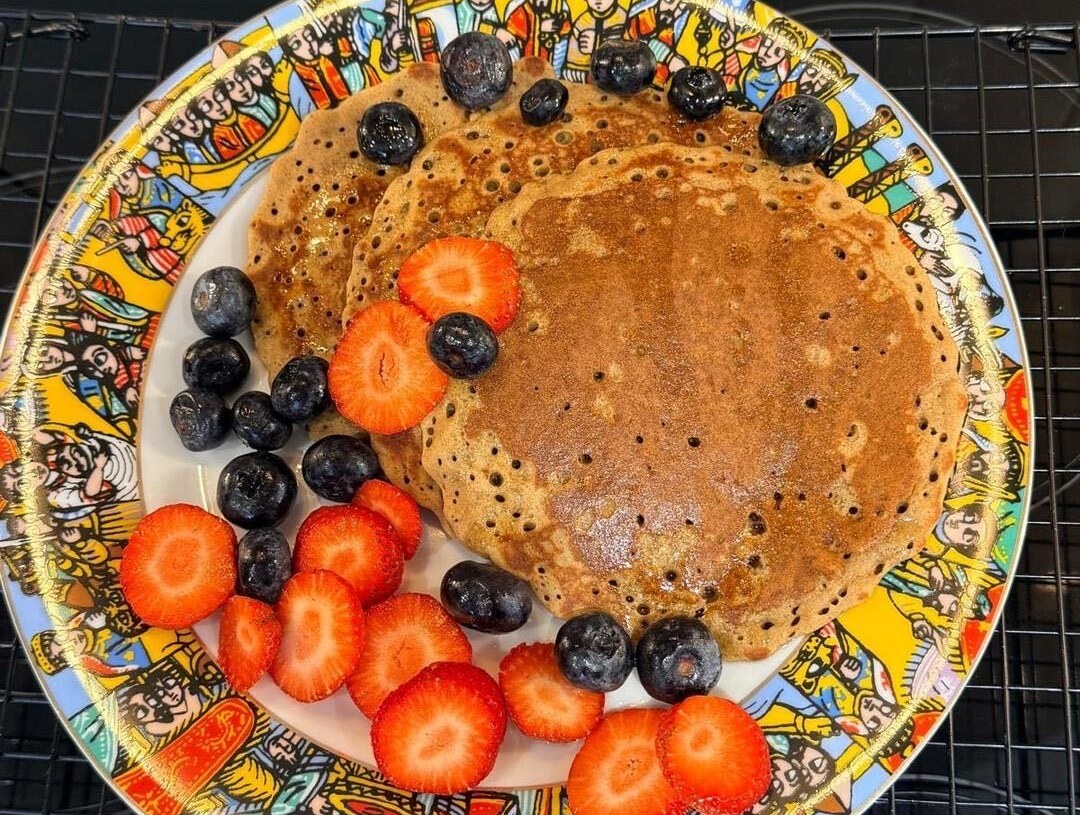 A stack of teff pancakes on a colourful Ethiopian plate with strawberries and blueberries